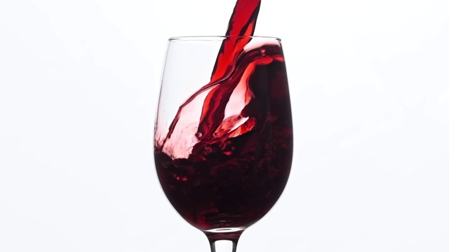 葡萄酒。红酒倒入酒杯中，背景为白色。中心组成。