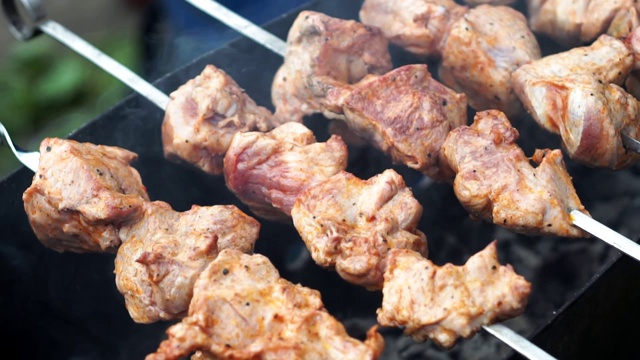 在户外用烤肉串烧肉，慢镜头。街头小吃、烧烤的概念