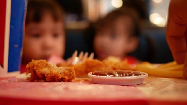 亚洲小女孩和她的妹妹在餐馆吃炸鸡和炸薯条。保健和食品理念。