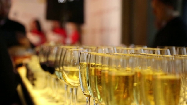 香槟倒进玻璃杯里。聚会的客人们过来喝一杯。酒保正在倒酒。都市夜生活的概念。