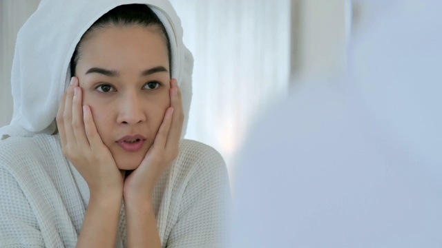亚洲年轻女性的脸颊有典型的问题，痤疮和丘疹在成年时期。年轻女性在浴室有皮肤问题。皮肤问题，痤疮，护肤理念