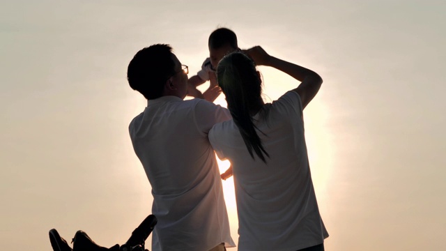 详情图-快乐的亚洲父亲，母亲和婴儿儿子愉快与乐趣沿海边的日落海浪在沙滩上。积极的父母和人在暑假与孩子户外活动。幸福的家庭假期。家庭、生活方式、人、人寿保险、假期