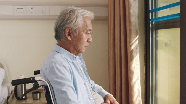 年长的亚洲人独自坐在轮椅上