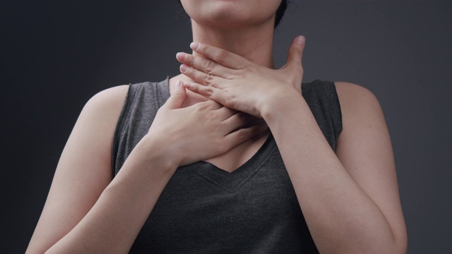 美丽的亚洲女人感觉不舒服在她的喉咙痛和难以吞咽的感冒和流感。患有腺体炎症的成年妇女。咽喉疼痛疾病保健和医疗