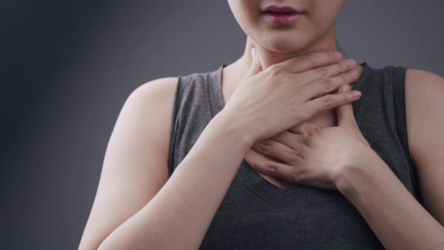 美丽的亚洲女人感觉不舒服在她的喉咙痛和难以吞咽的感冒和流感。患有腺体炎症的成年妇女。咽喉疼痛疾病保健和医疗