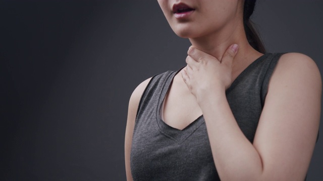 美丽的亚洲女人感觉不舒服在她的喉咙痛和难以吞咽的感冒和流感。患有腺体炎症的成年妇女。咽喉疼痛疾病保健和医疗