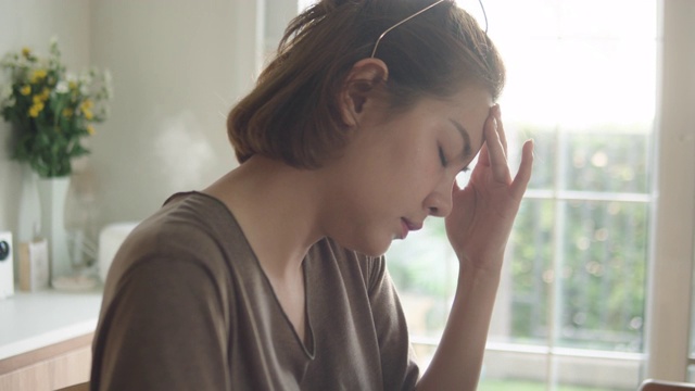 一位亚洲女性在家里使用笔记本电脑时遇到了困难。