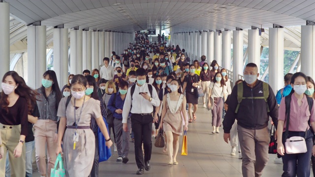 4K分辨率的亚洲人群在早高峰时间在曼谷上班时戴着防冠状病毒或新冠病毒防护面罩和空气中的微尘pm 2.5