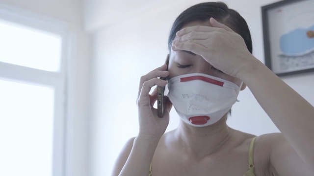 亚洲妇女戴口罩保护冠状病毒，呼叫紧急服务占领者