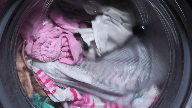 洗衣服的特写镜头。洗衣机滚筒转动，卫生，洗衣