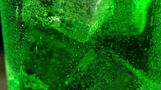详情图-冰冷的冰块漂浮在绿色的泡沫鸡尾酒中旋转。