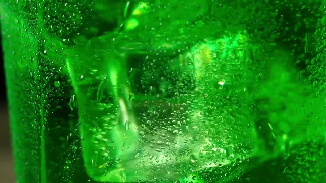 详情图-冰冷的冰块漂浮在绿色的泡沫鸡尾酒中旋转。