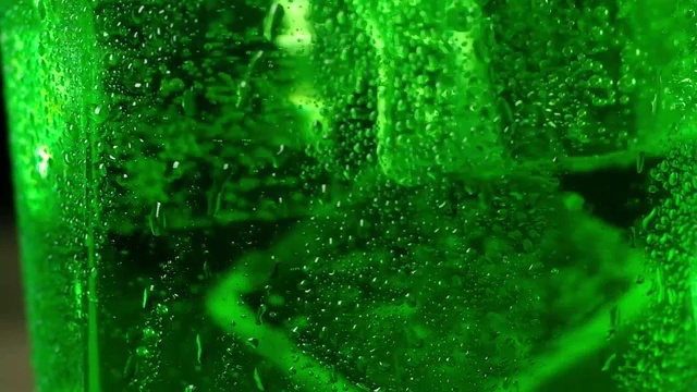 详情图-冰冷的冰块漂浮在绿色的泡沫鸡尾酒中旋转。