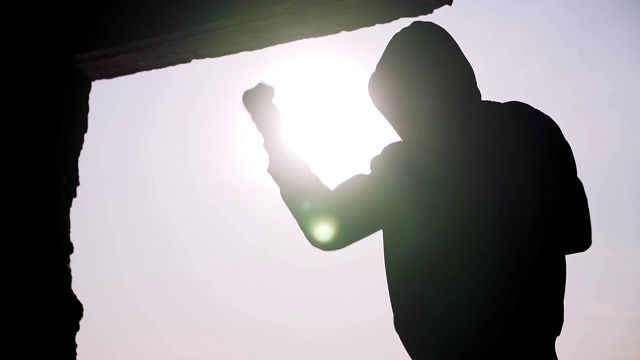 日落背景上一个拳击手的剪影。教练手下留情。太极拳。户外锻炼。励志的视频。健康的生活方式和运动的主题。武术。拳击。缓慢的运动。静态帧