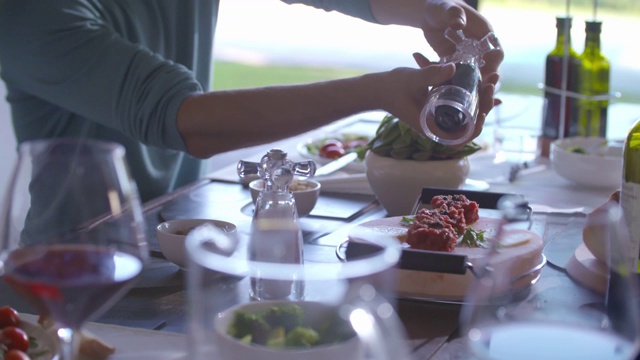 详情图-餐桌上用胡椒瓶调味的烤肉细节。手手持特写。男人烤肉的细节