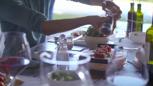 详情图-餐桌上用胡椒瓶调味的烤肉细节。手手持特写。男人烤肉的细节