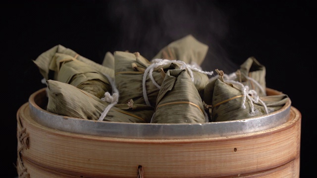 煮粽子-蒸中国粽子在蒸笼，新鲜准备的食物端午节孤立在黑色的背景，接近生活方式。