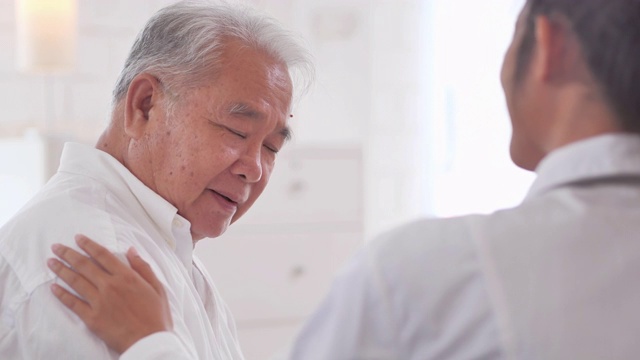 亚裔老年男子听着年轻的黑人女护士医生在家给他年长的男性病人咨询。采购产品医疗，护理，护理，退休，志愿者，慈善，教育，养老院，在家照顾者，医药和卫生保健