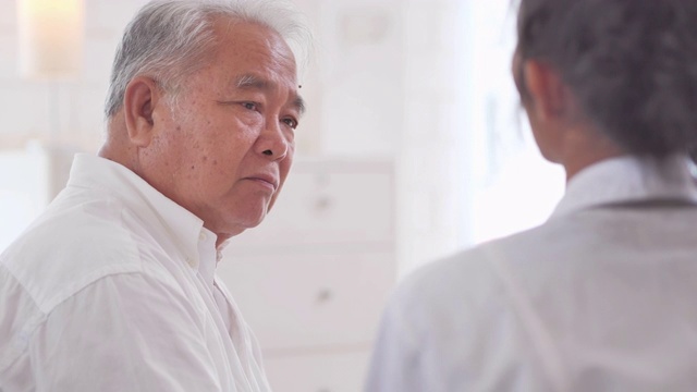 詳情圖-亞裔老年男子聽著年輕的黑人女護士醫(yī)生在家給他年長的男性病人咨詢。采購產(chǎn)品醫(yī)療，護理，護理，退休，志愿者，慈善，教育，養(yǎng)老院，在家照顧者，醫(yī)藥和衛(wèi)生保健
