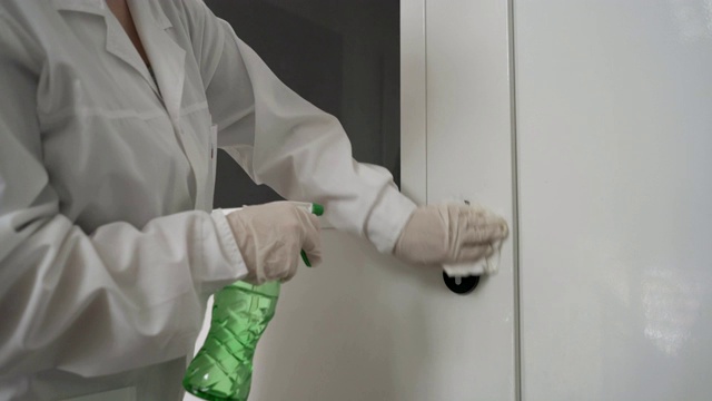 妇女用湿纸巾和酒精消毒剂喷雾消毒门把手。消毒卫生保健，抗冠状病毒病
