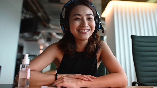 一位亚洲华裔美丽的女白领带着口罩对着摄像机进行视频通话，与他的商业伙伴进行视频会议