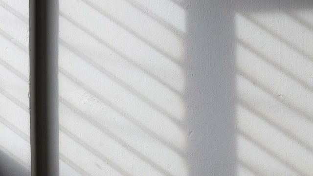 时间流逝:阳光的背景透过窗户照在白色的混凝土墙上。