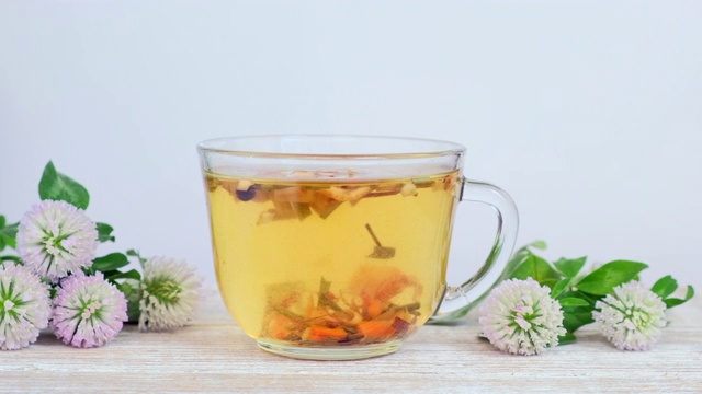 详情图-玻璃杯中的草药茶，白色背景上有野花-三叶草花