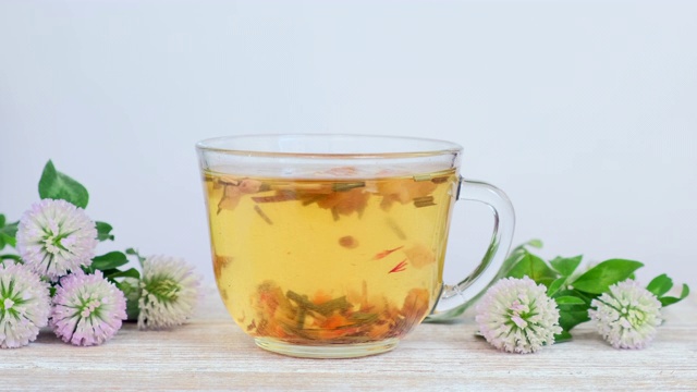 详情图-玻璃杯中的草药茶，白色背景上有野花-三叶草花