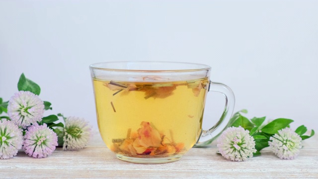 详情图-玻璃杯中的草药茶，白色背景上有野花-三叶草花
