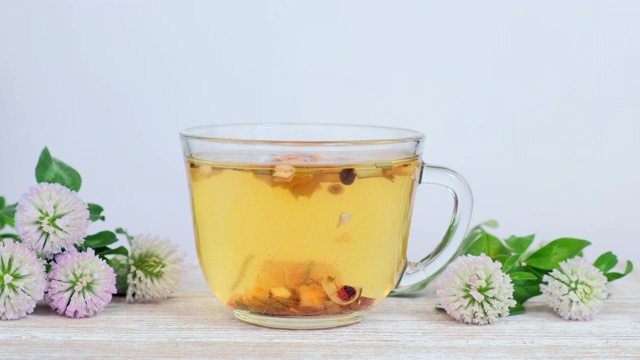 详情图-玻璃杯中的草药茶，白色背景上有野花-三叶草花