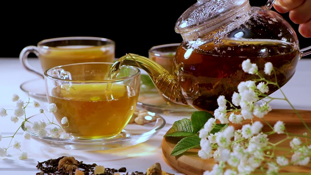 将热绿茶从玻璃茶壶倒入玻璃杯。茶道和传统。桌上自制茶。