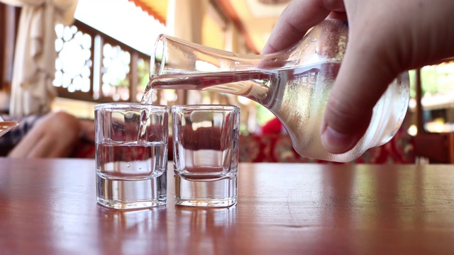 手从醒酒器中向玻璃杯中倒入伏特加