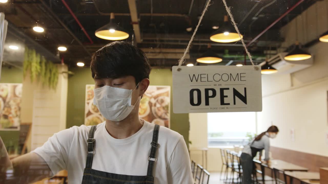 詳情圖-在封鎖和冠狀病毒covid-19疫情后，一名亞洲男子在一家餐館工作，打開前面的開放標(biāo)志開門