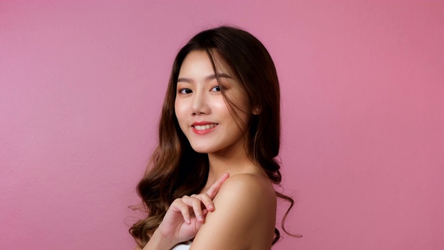 美丽的年轻亚洲女人短发与干净新鲜的皮肤。面部护理，面部治疗，美容，美丽和健康的皮肤和化妆品理念概念。女性美丽皮肤孤立。亚洲女性幸福的粉红色背景。