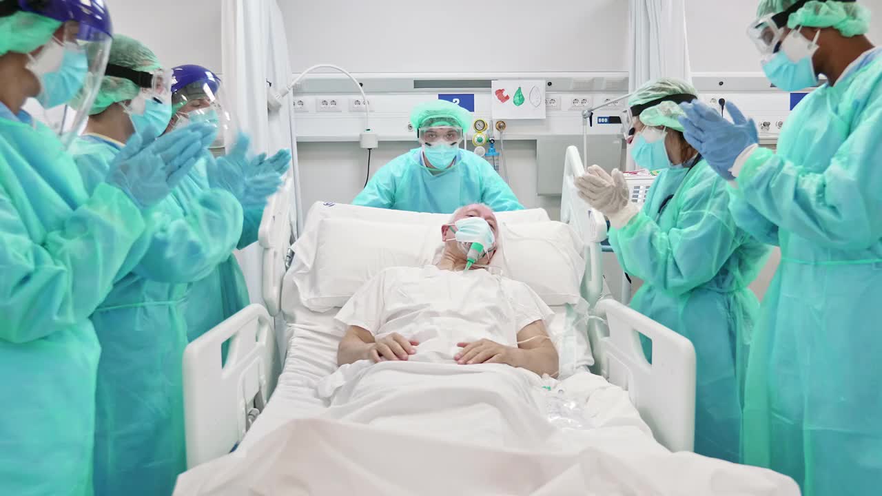 医生和护士鼓掌老年病人离开重症监护室