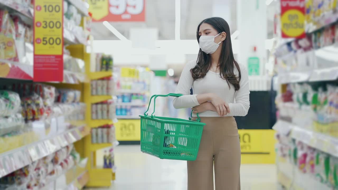 戴着口罩的女人在超市购物和检查食品货架