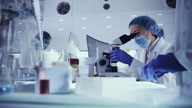 研究有害生物样本的女性小组。亚洲女医生使用显微镜