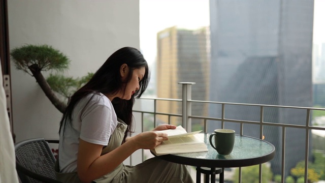 一个亚洲年轻女子在阳台上看书