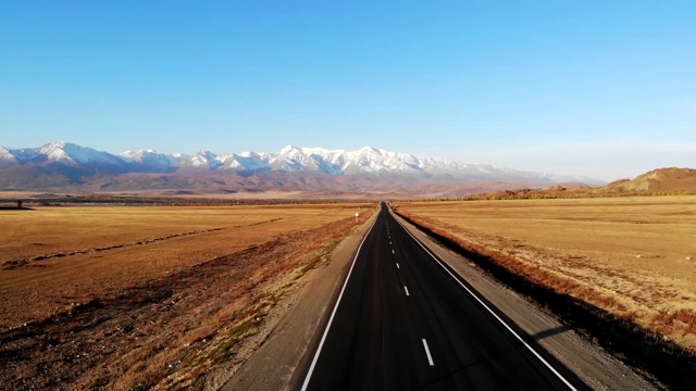 在阿尔泰，一个晴朗的秋日，在高速公路上驾驶着四旋翼飞行器，背景是群山