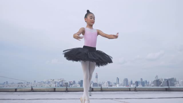年轻的芭蕾舞演员和芭蕾舞演员在楼顶跳舞，优雅的女子在芭蕾舞中旋转