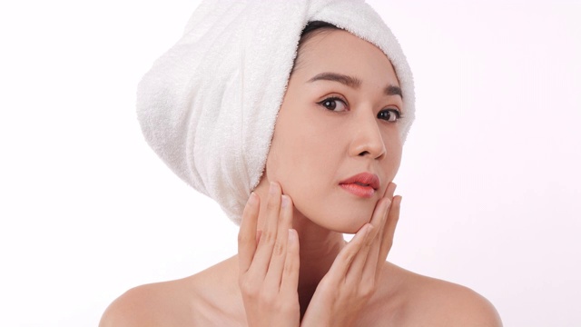 亚洲美丽的女人检查她的脸在白色的背景。