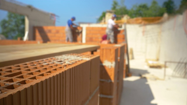 特写，自由度:承包商砌砖和建筑墙壁的模糊镜头。