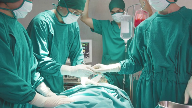 一群亚洲医生、护士和外科医生手中拿着医疗器械，看着病人并做手术。团队合作，医疗保健和医疗理念。外科医生会说话并使用器械。