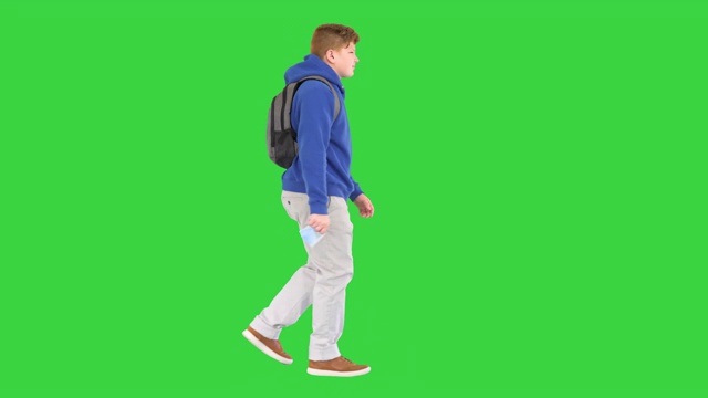 穿着便服的学童在绿屏上走着，摘下医用口罩
