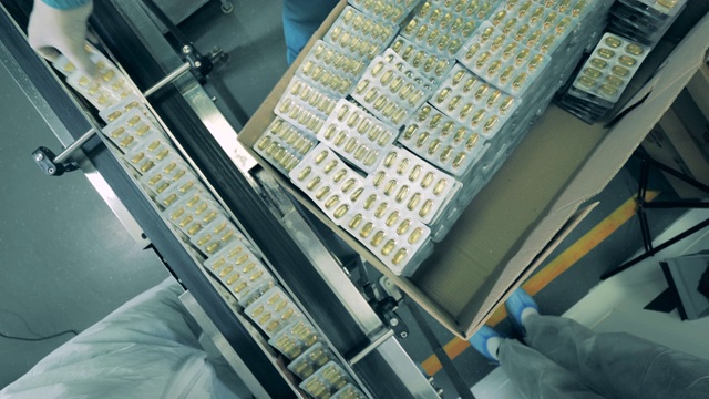 制药学、制药概念。化工工人正在把泡好的胶囊装进盒子里