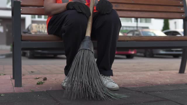 一个清洁女工坐在街上的长凳上。隔离期间院子的清洁和秩序取决于看门人。