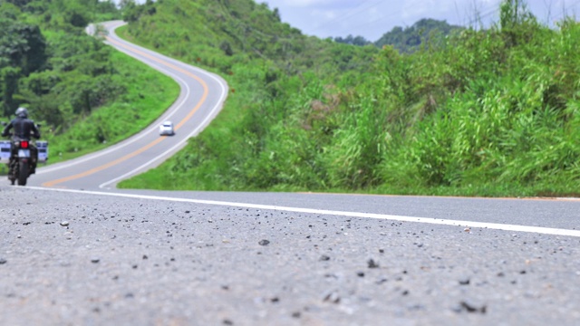 场景散焦的男子驾驶一辆摩托车在道路上翻山越岭在泰国北部