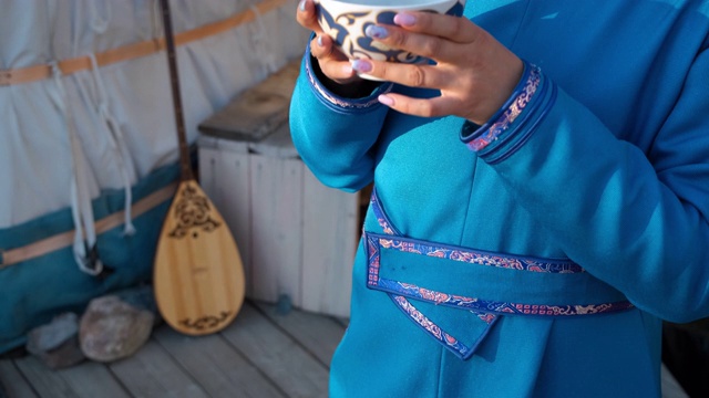 穿着亚洲服饰的女人在毡房附近喝茶
