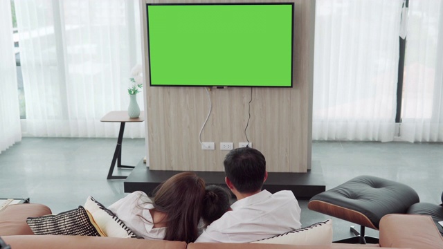 詳情圖-亞洲幸福家庭坐在家里的客廳看電視，一起度過寶貴的時間，頻道到綠色屏幕顯示器為您的信息
