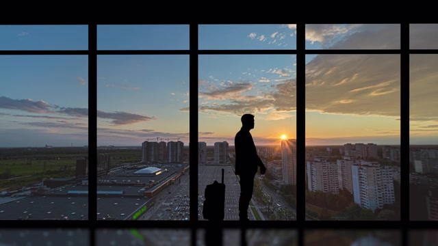 详情图-在清晨的城市背景下，提着箱子的男子站在室内。时间流逝
